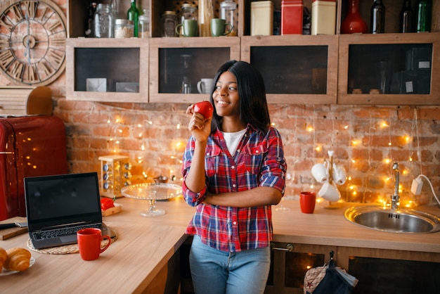 Cheerful black woman cooking on the kitchen