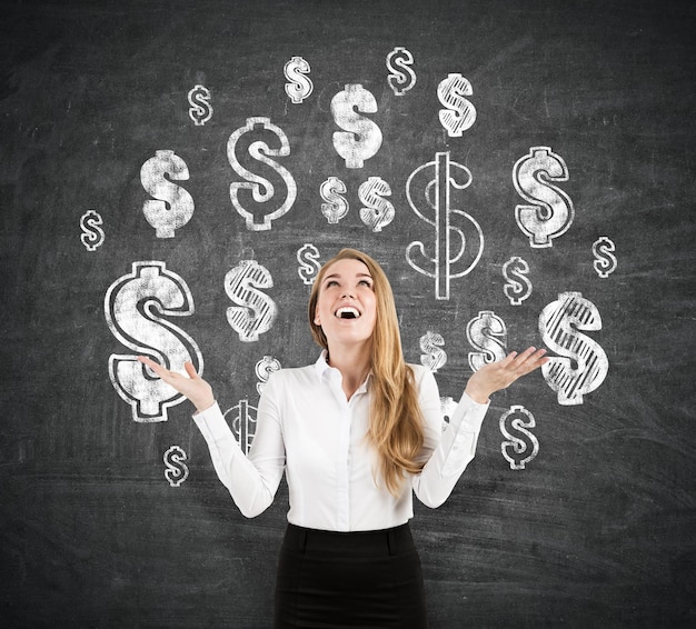 Cheerful blond businesswoman near blackboard with dollar signs