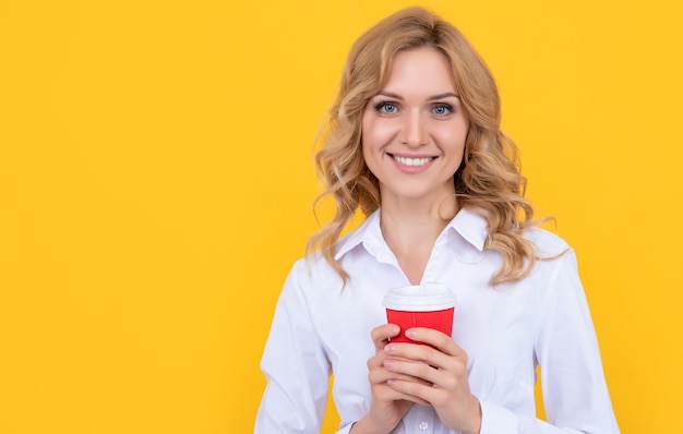 黄色の背景にコーヒーカップと陽気なブロンドの女性