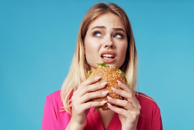 Cheerful blonde fast food snack emotion blue background High quality photo