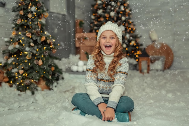 cheerful blonde girl in a hat on the background of a wooden house in winter