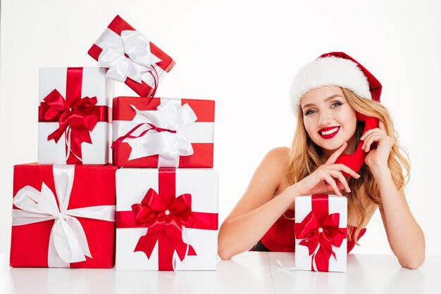 Cheerful blonde woman calling next to gift boxes