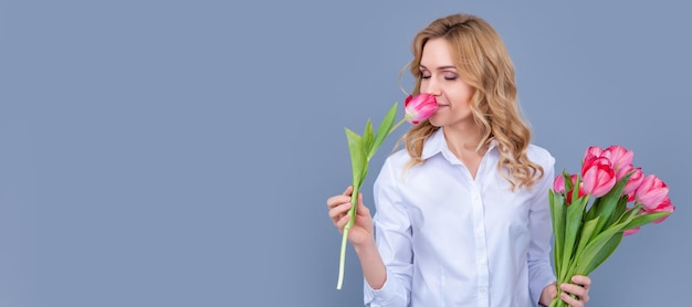 Cheerful blonde woman with spring tulip flowers on grey background Woman isolated face portrait