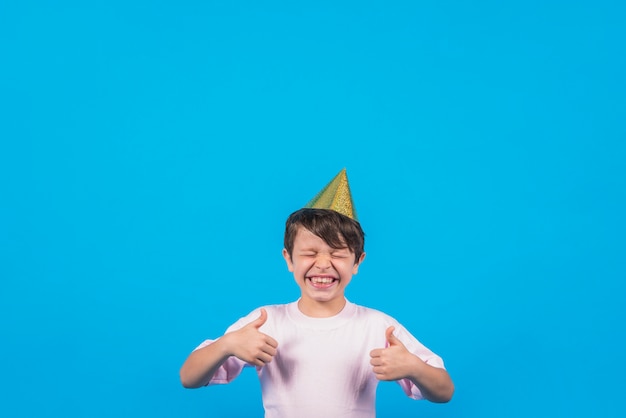 Foto ragazzo allegro che gesturing thumbup contro il contesto della sfuocatura