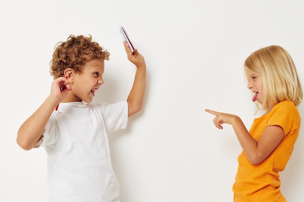 Cheerful boy and girl stand side by side posing light background