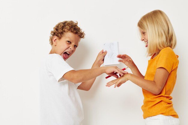 Cheerful boy and girl stand side by side posing light background