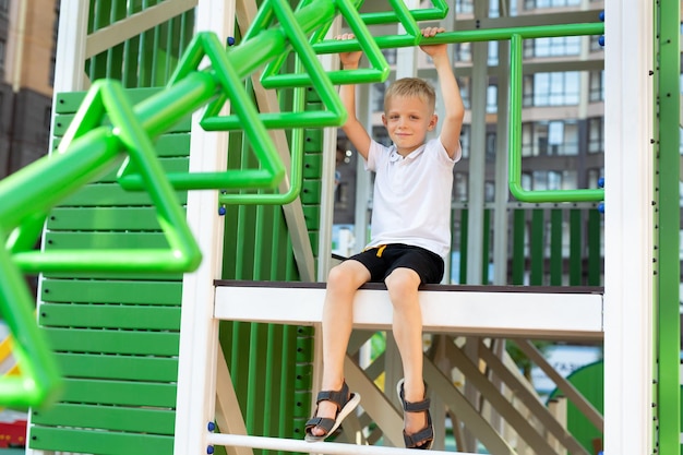 A cheerful boy is playing on a modern playground on the street