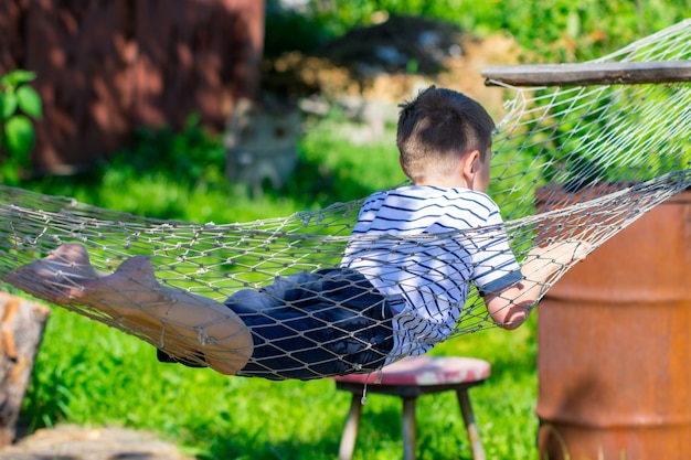 庭のハンモックに横たわっている陽気な少年。