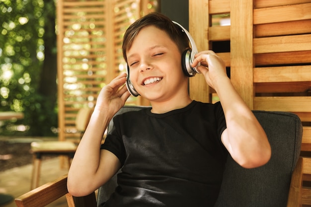 Cheerful boy sitting in cafe nature listening music