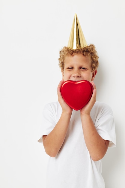 Cheerful boy with a cap on his head a gift box in the form of a heart