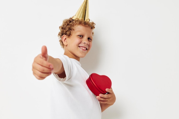 Cheerful boy with a cap on his head a gift box in the form of a heart