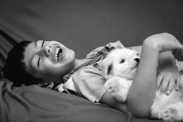 Photo cheerful boy with dog lying on bed