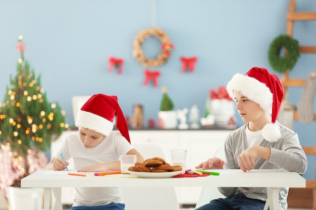 Cheerful boys painting with crayons in decorated Christmas room
