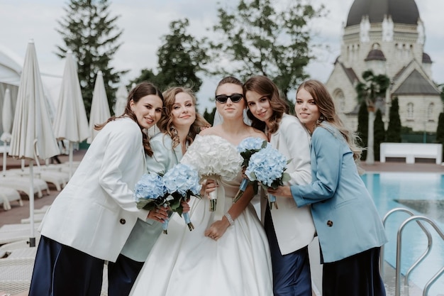 Cheerful bride and bridesmaids with bouquets posing outdoors