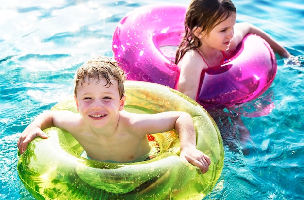 Cheerful brother and sister swimming in the pool