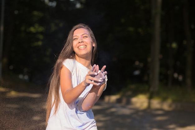 Cheerful brunette asian woman having fun with dry paint on Holi festival