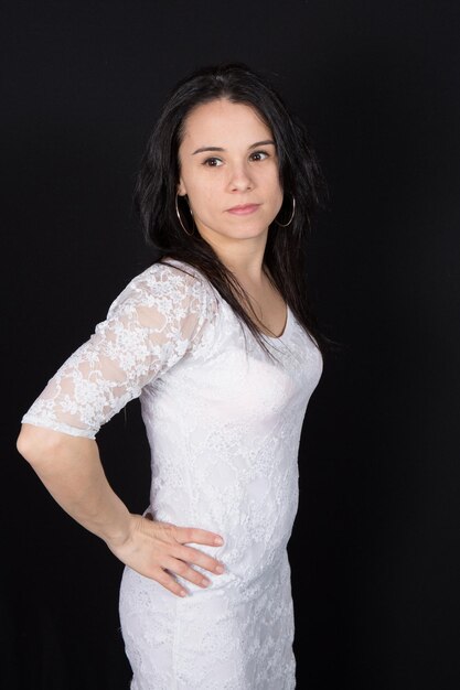 Cheerful brunette in white dress on black background