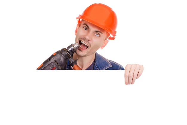 A cheerful builder holds a drill in his hand on an isolated white background Emotional photo