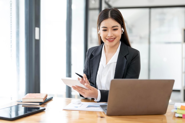 Cheerful business lady working on laptop and calculator in office Asian happy beautiful businesswoman in formal suit work in workplace