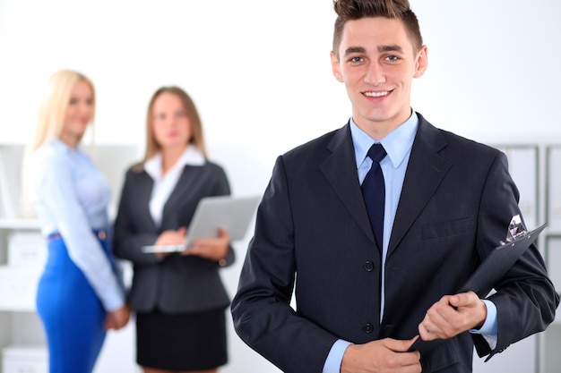 Cheerful business man in office with colleagues in the background, start-up team.