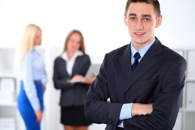 Cheerful business man in office with colleagues in the background, start-up team.