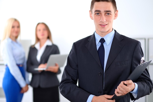 Cheerful business man in office with colleagues in the background, start-up team.