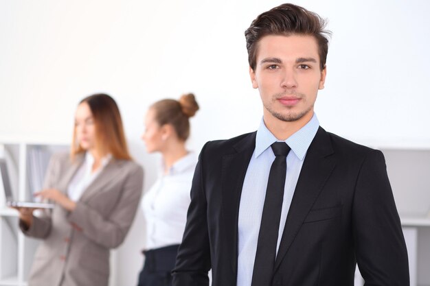 Cheerful business man in office with colleagues in the background, sturt  up team