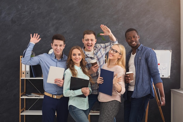 Photo cheerful business people in office. successful young team posing for photo, greeting and smiling at camera, motivation and success concept, copy space