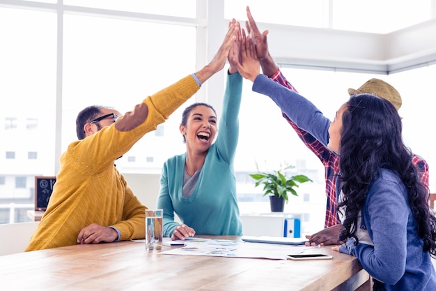 Cheerful business team doing high five while sitting in creative office