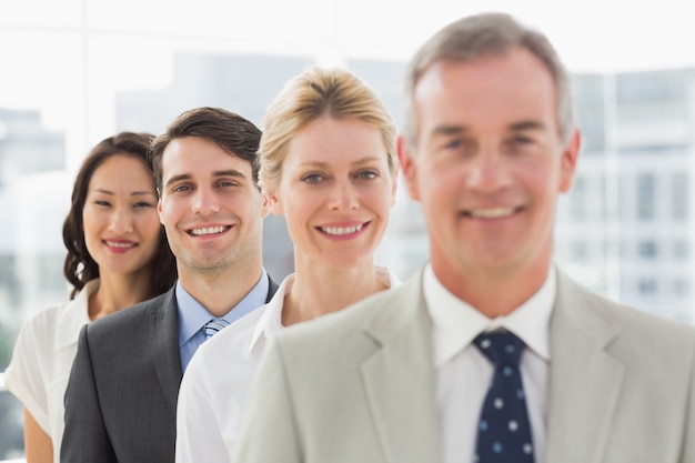 Cheerful business team standing in a line smiling at camera