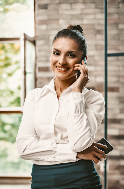 Cheerful Business woman Using Phone in Office Interior