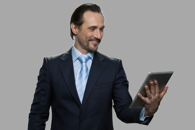 Cheerful businessman having video chat. Smiling caucasian man in business suit happily talking through digital tablet webcam.