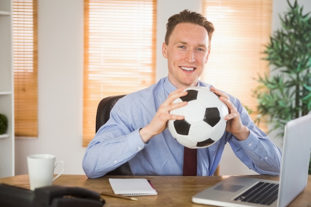 Cheerful businessman holding a soccer ball