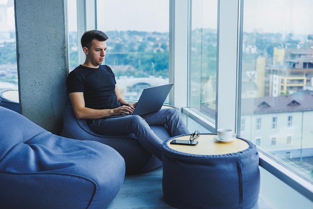 Веселый бизнесмен сидит за ноутбуком в офисе Бизнесмен сидит и работает за ноутбуком Начало дня в офисе