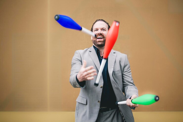 Photo cheerful businessman juggling bottles against wall