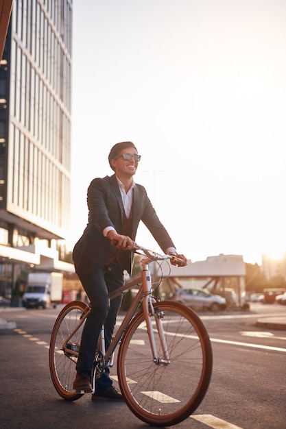 Cheerful businessman riding bike on street