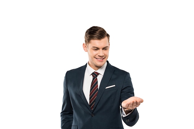 Cheerful businessman in suit looking at hand isolated on white