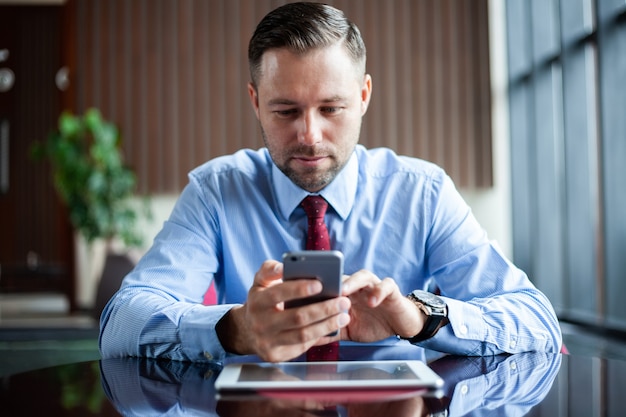 Cheerful businessman using cellphone for communication while sitting in a coffee shop