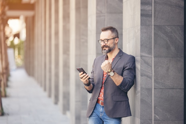 Cheerful businessman using mobile phone and screaming of joy in the city