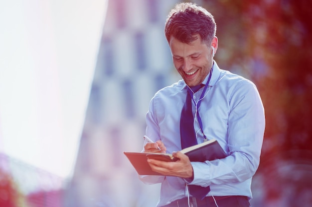 Cheerful businessman writing in dairy