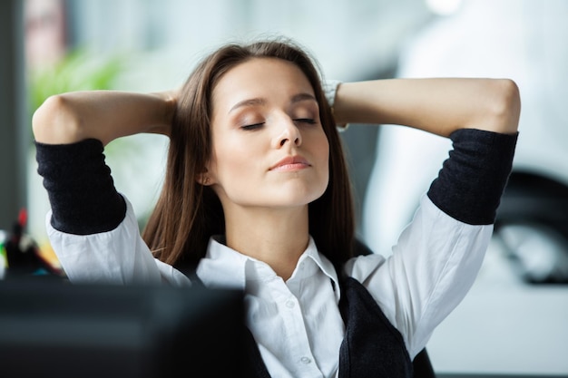 Cheerful businesswoman dreaming at workplace Female office worker takes break after job done Business lady relaxing at work