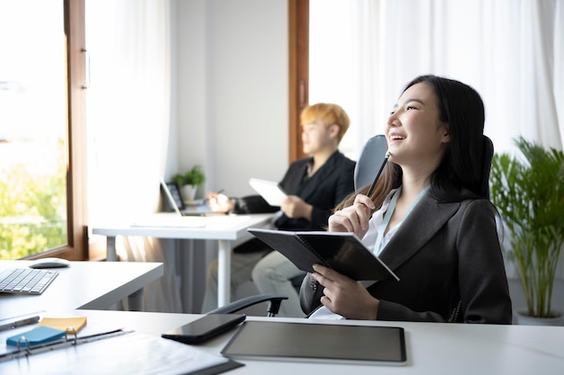 Cheerful businesswoman sitting on comfortable office chair and looking out of window.