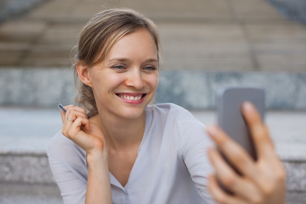 Cheerful businesswoman taking selfie outdoors