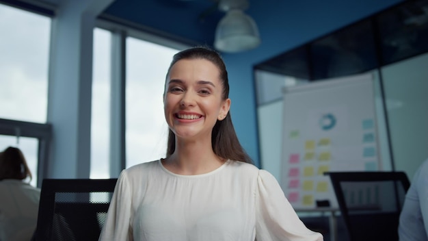 Cheerful businesswoman talking with colleague online by video chat at workplace