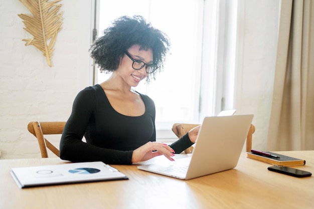 Cheerful businesswoman working on laptop in a cozy workspace with natural light