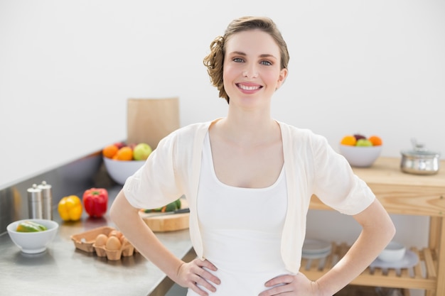 Cheerful calm woman posing in kitchen with hands on hips