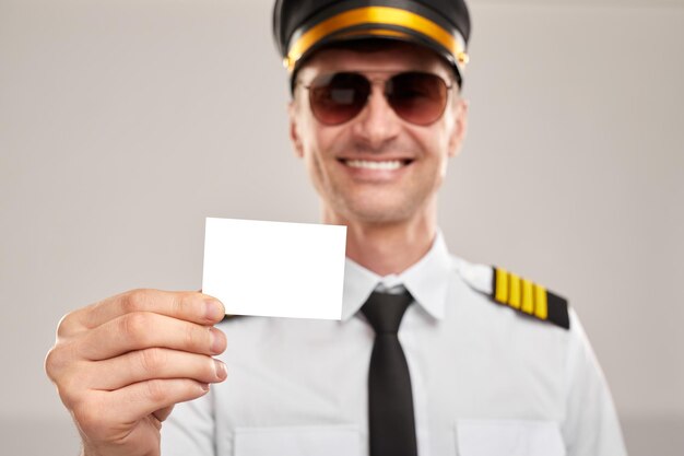 Cheerful captain showing business card