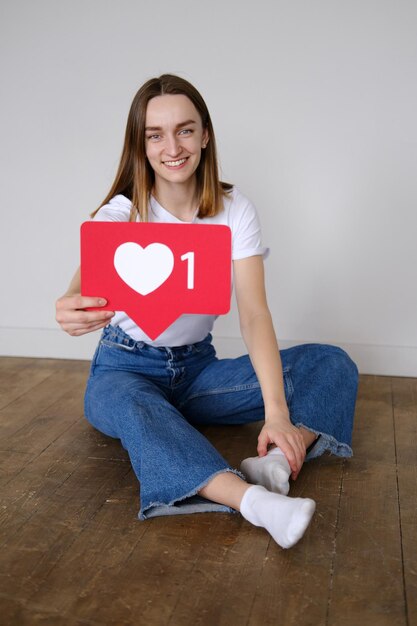 cheerful carefree woman holding heart like icon of social media