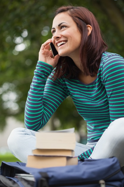 Studente casuale allegro che si siede sulla telefonata del banco