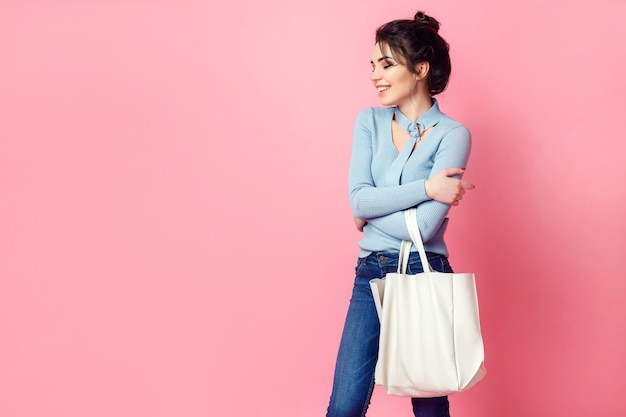 Cheerful casual young woman with bag looking away